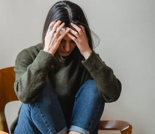 Woman holding her head down in distress, representing the emotional weight of anxiety.