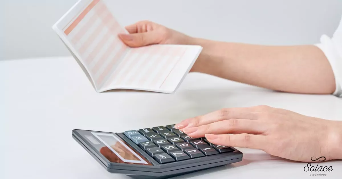 calculator-paperwork-hand-saving-adhd-assessment-costs-insurance-rebates Hand holding a calculator and paperwork representing tips to reduce ADHD assessment costs through insurance and Medicare rebates.