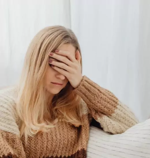 what-causes-social-anxiety Woman holding her head, experiencing symptoms related to social anxiety treatment in Melbourne